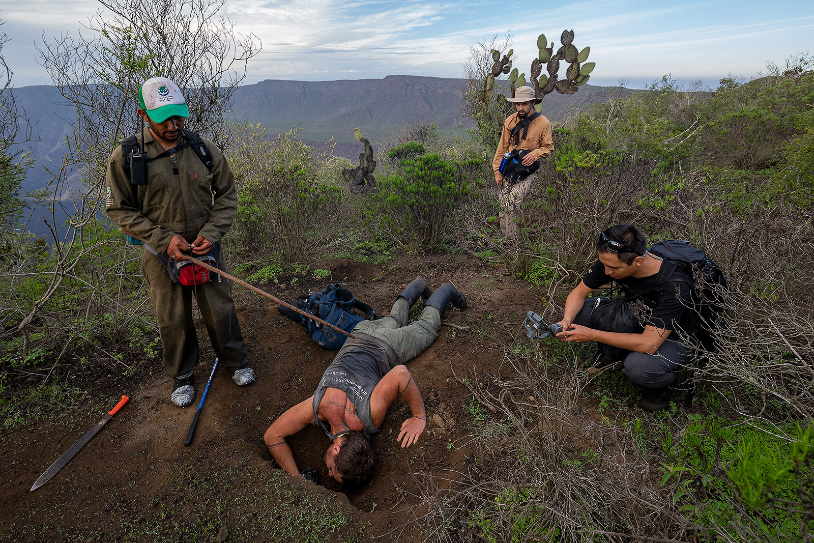 Biologist Jose Vieira dives inside the burrow of a Pink Land-Iguana